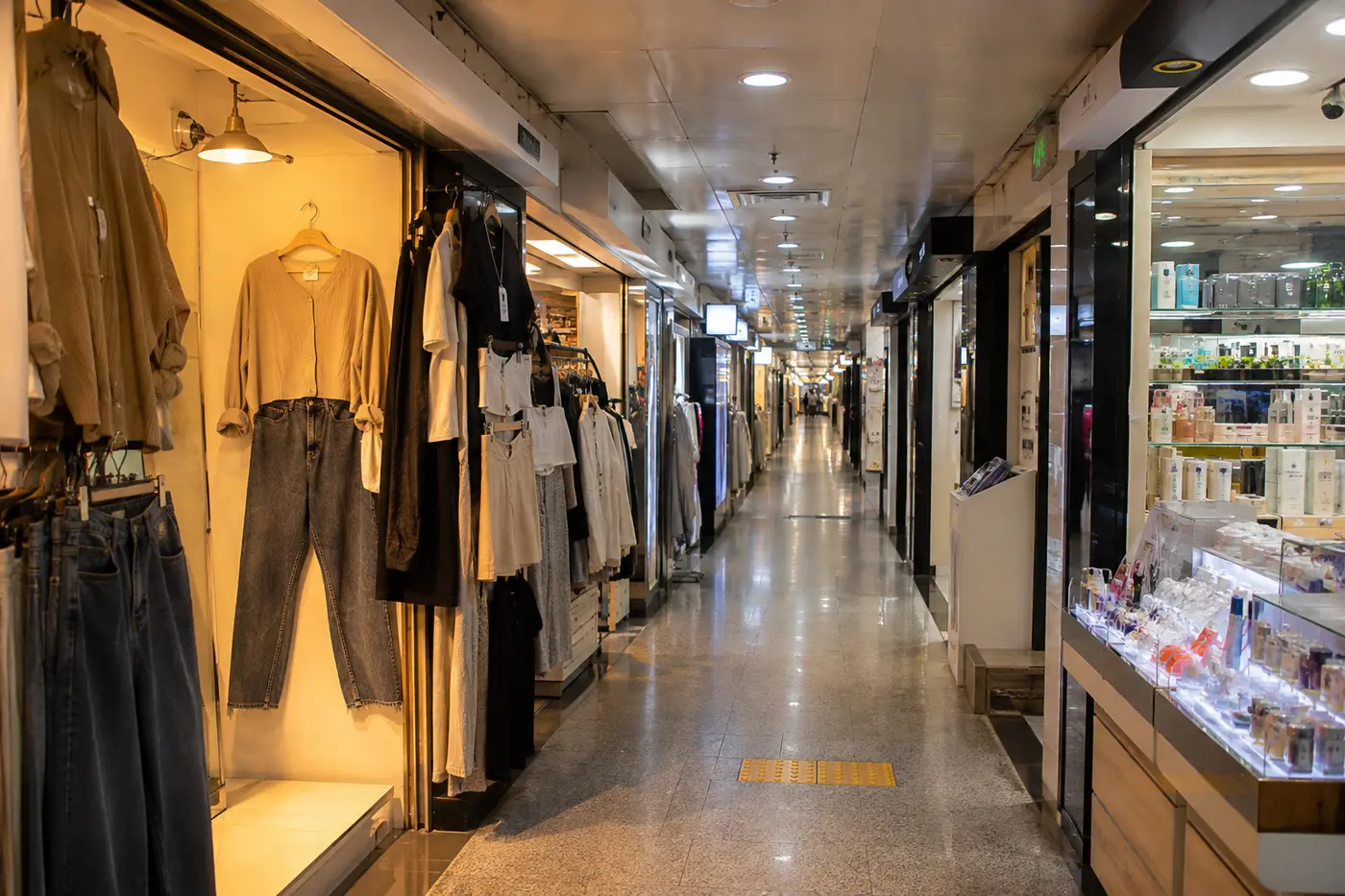 A compact Gangnam underground arcade with fashion and cosmetic storefronts