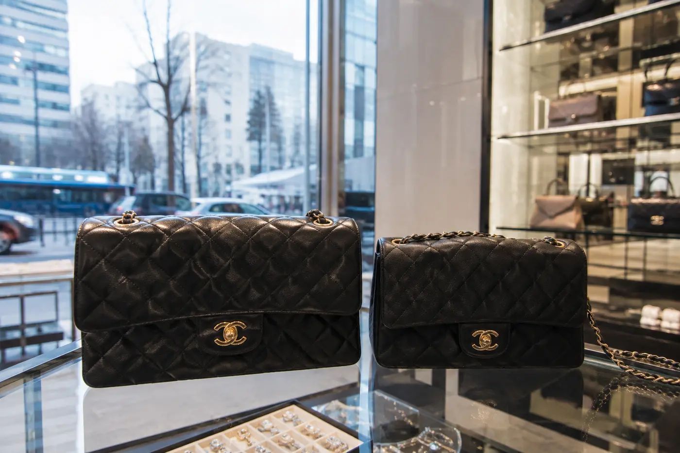 A classic black flap bag comparison beside exchange-rate and regional price notes