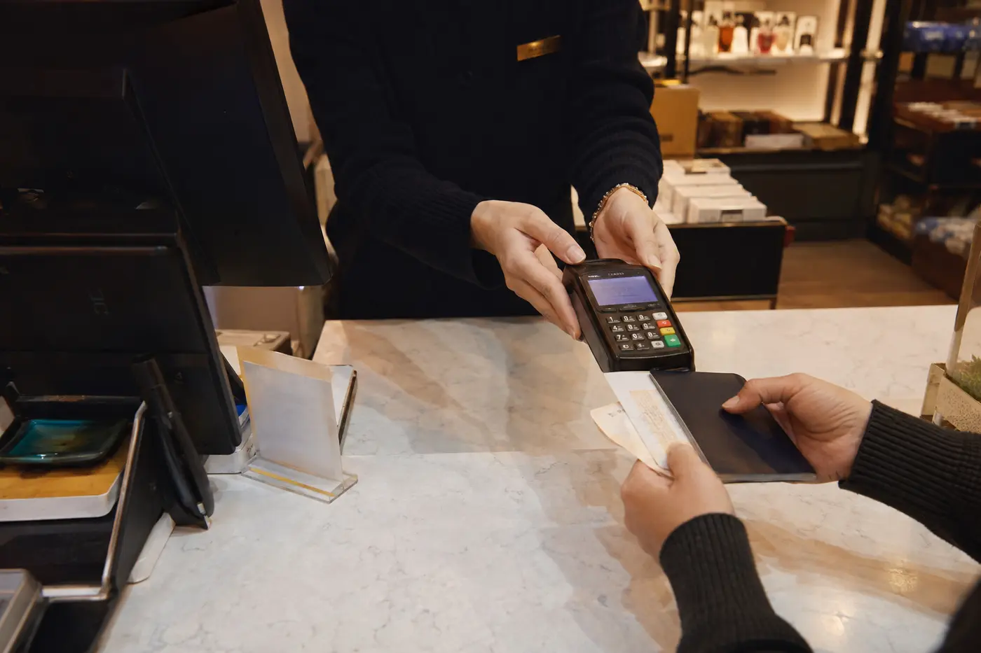 A cashier processing an immediate tourist tax refund with passport and card terminal