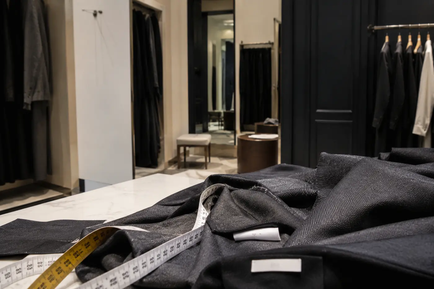 Eine Umkleidekabine mit Maßband, Etiketten und Blick auf die Verarbeitung eines Kleidungsstücks