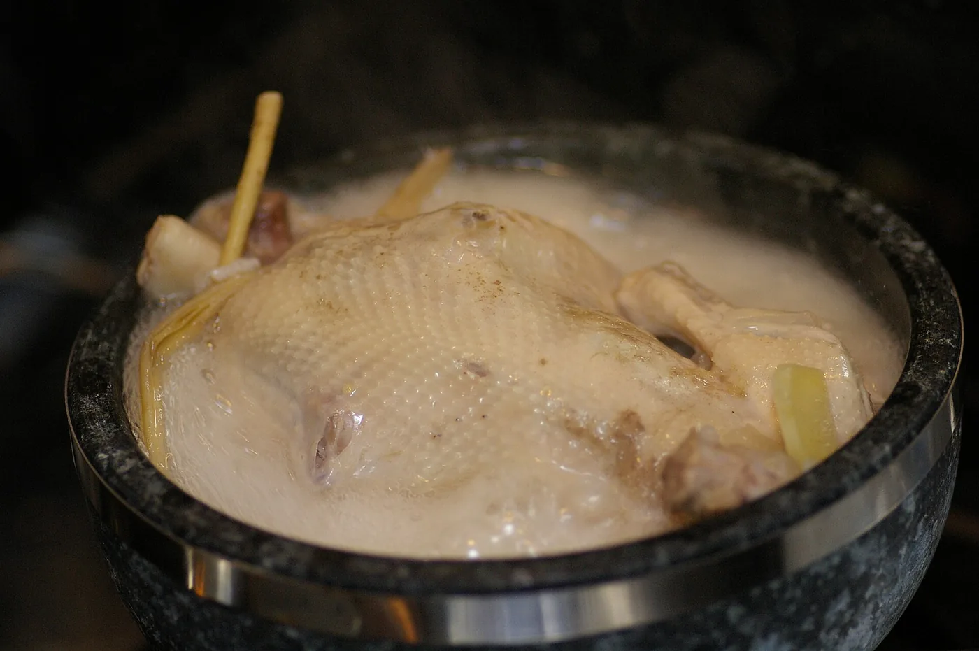 A whole young chicken in a bowl of samgyetang broth