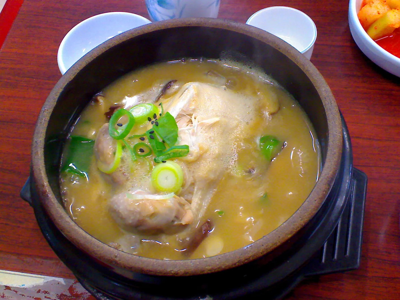 A whole young chicken in a bowl of samgyetang broth