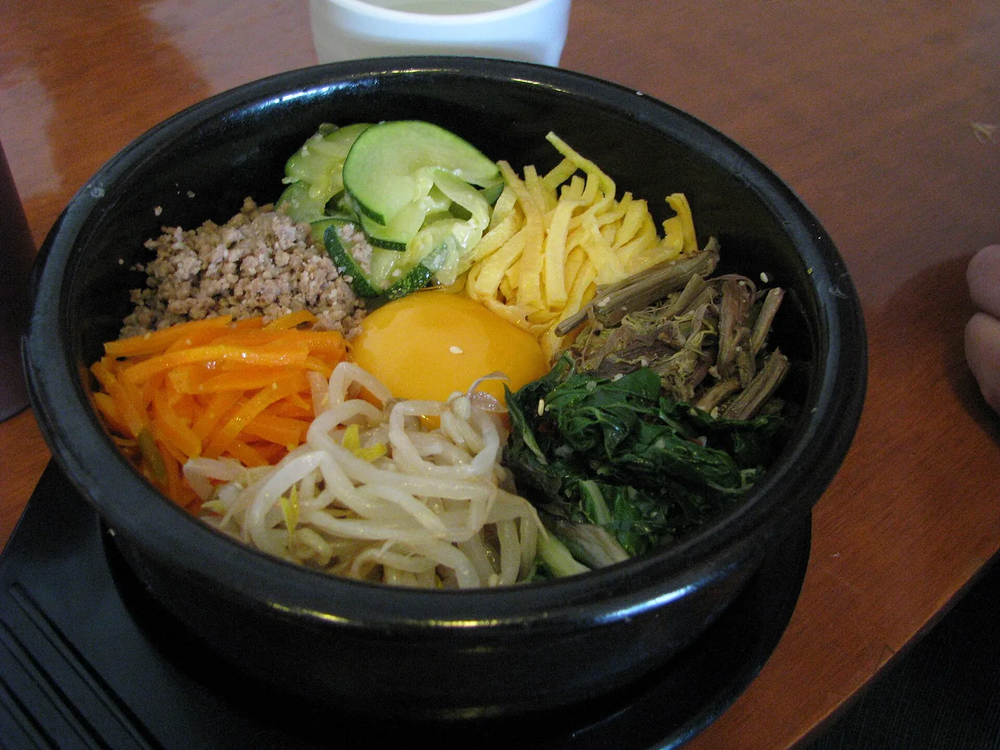 A bowl of bibimbap topped with vegetables, beef and egg