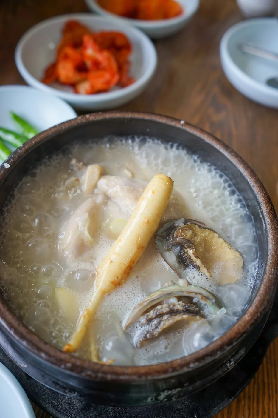 A whole young chicken in a bowl of samgyetang broth