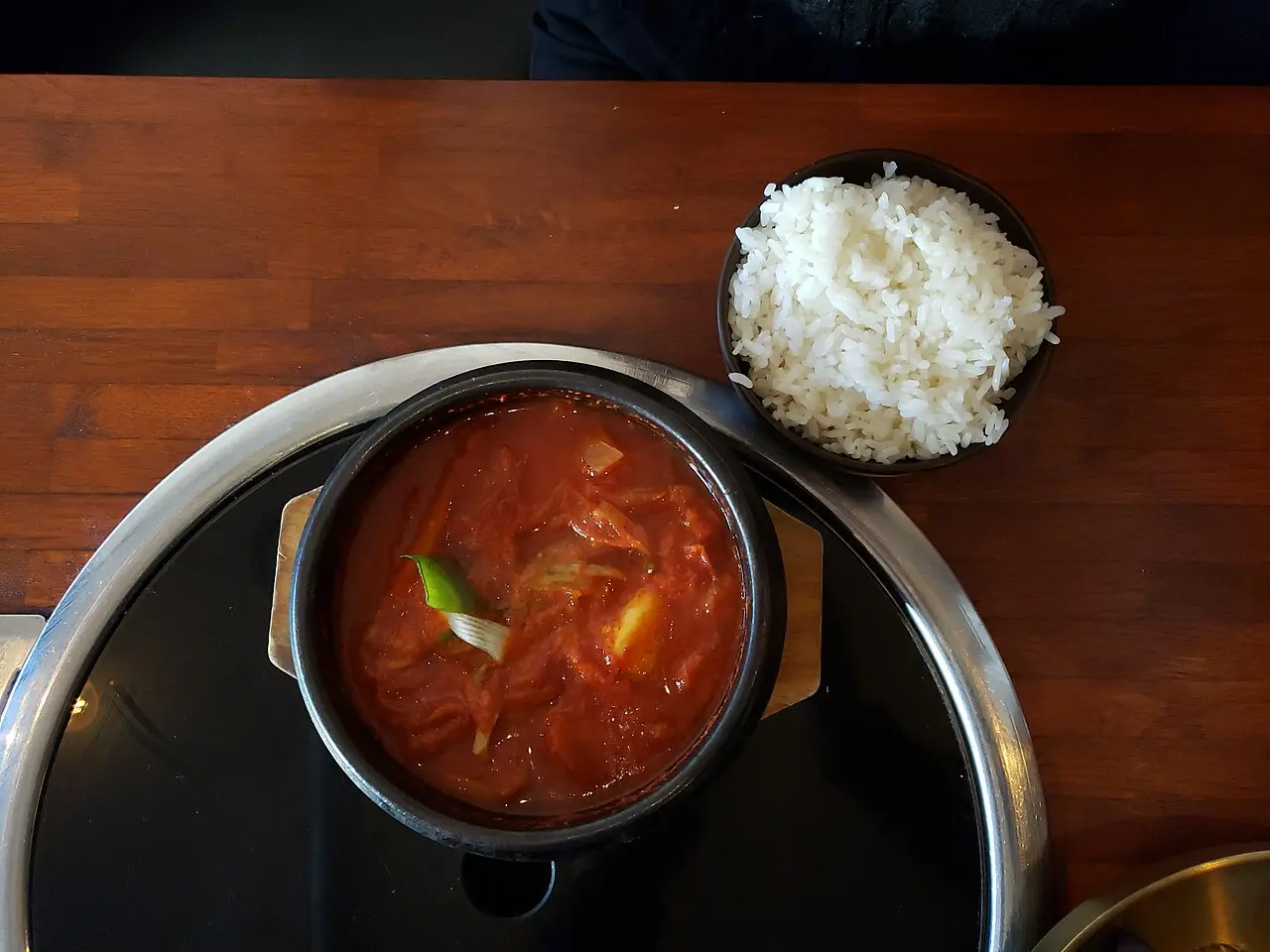 A bubbling bowl of red kimchi jjigae served with rice