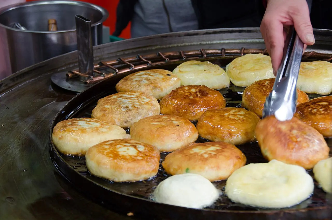 Round hotteok pancakes browning on a market griddle