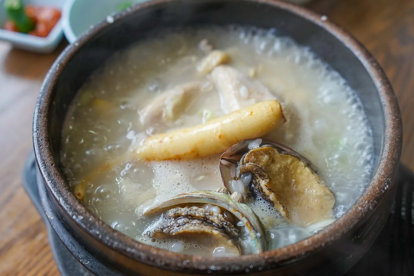 A whole young chicken in a bowl of samgyetang broth