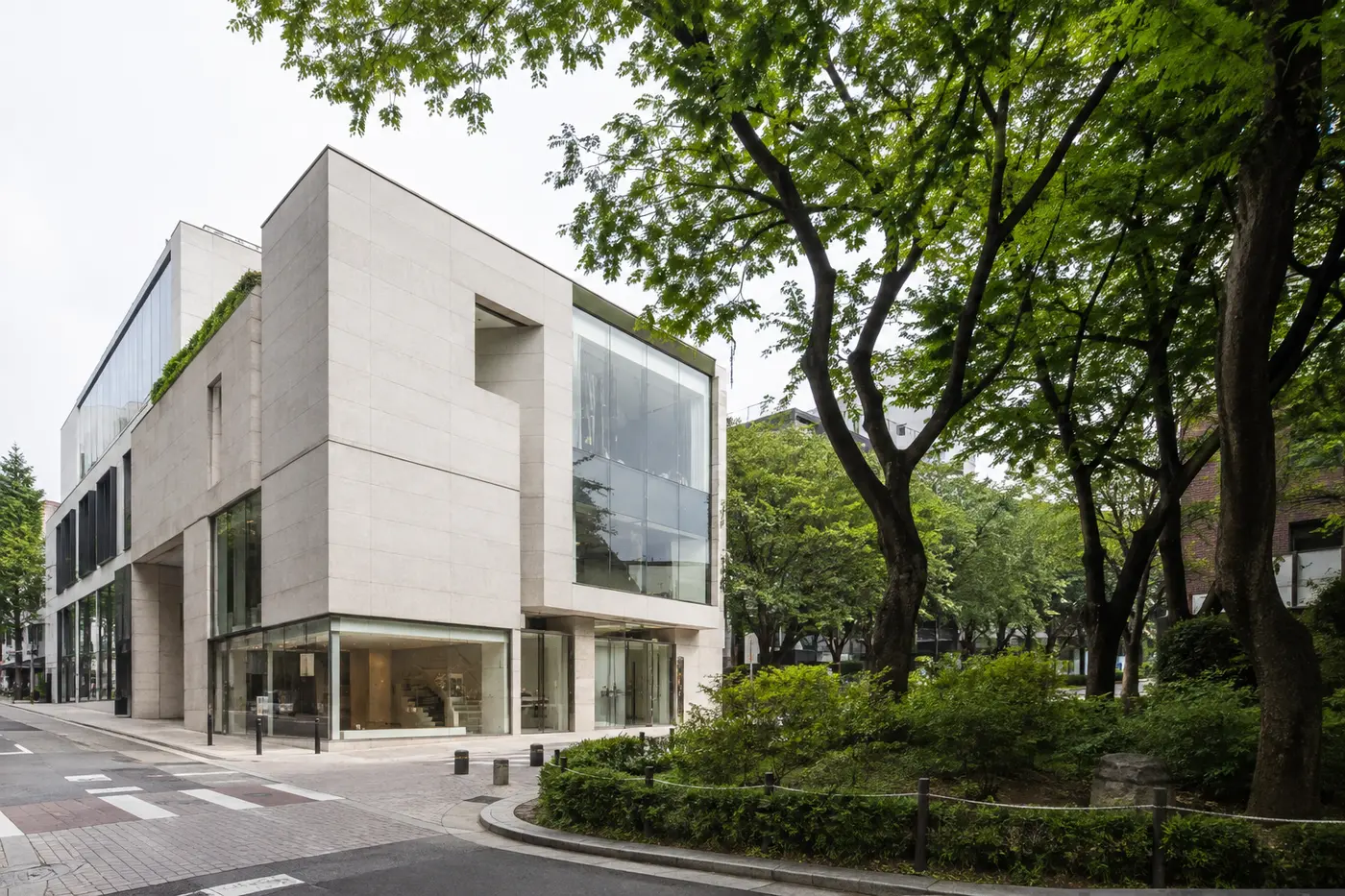 A sculptural stone-and-glass flagship beside the greenery of Dosan Park