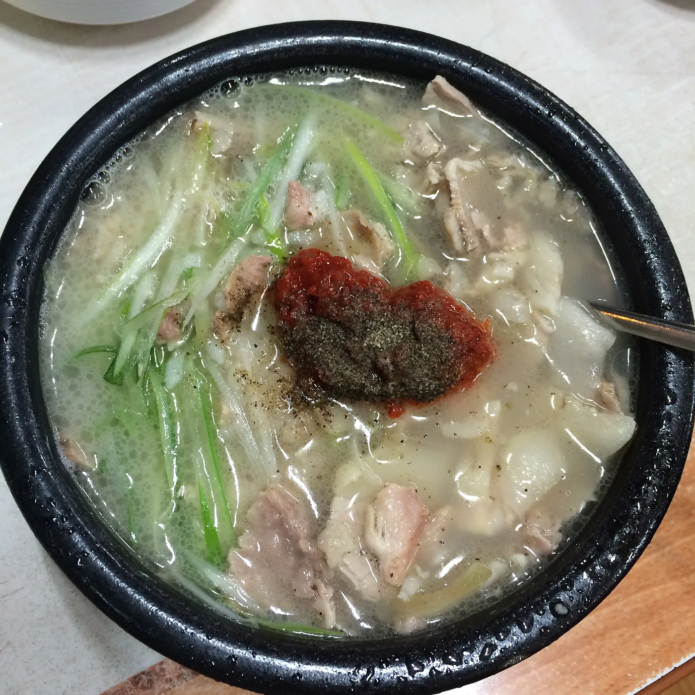 Busan pork and rice soup with sliced pork and chives